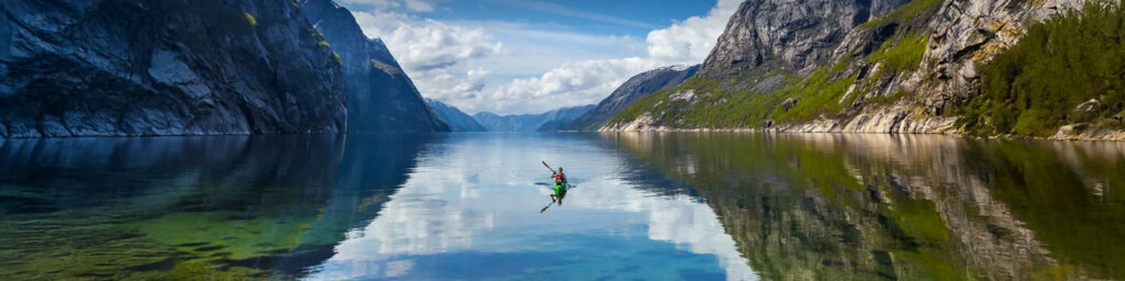 Person in a kayak floating on a magestic Norwegian Fjord